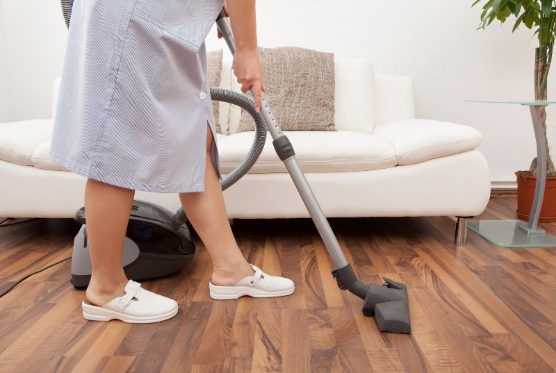 A professional cleaner vacuuming a hardwood floor
